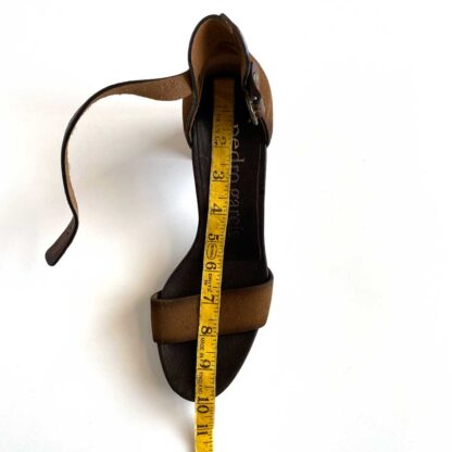 Overhead view of heeled sandals with a tape measure to indicate the length of the footbed at just under 10 inches.