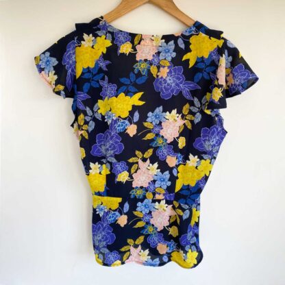 Rear view of a preloved Banana Republic floral wrap blouse in a blue, yellow and pink print