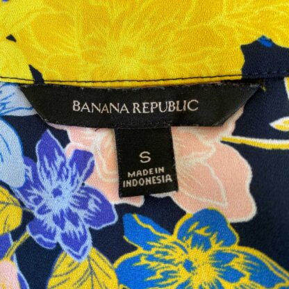 Close up of a preloved Banana Republic floral wrap blouse in a blue, yellow and pink print, showing the brand label and size tag