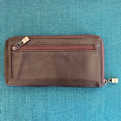 Overhead view of the back side of a vintage Perlina large leather wallet, showing the zipper pocket with logo zipper pull as well as the zipper and logo zipper pull around the entire wallet.