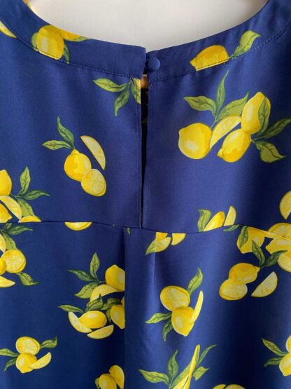Close up of a blouse showing the rounded neckline and lemon print