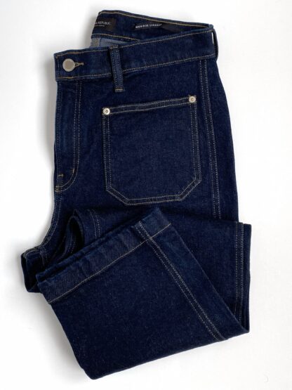 a full overhead view of a pair of Banana Republic cropped denim pants in dark wash folded with the cuff by the pocket