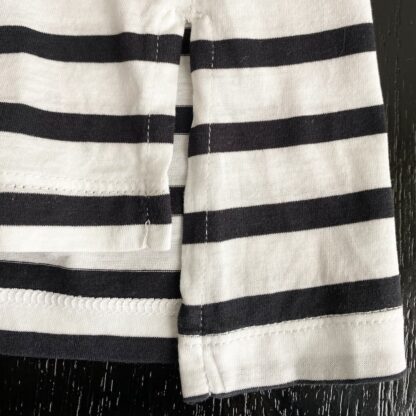 close up view of the side slit in a black and cream striped Banana Republic tee.